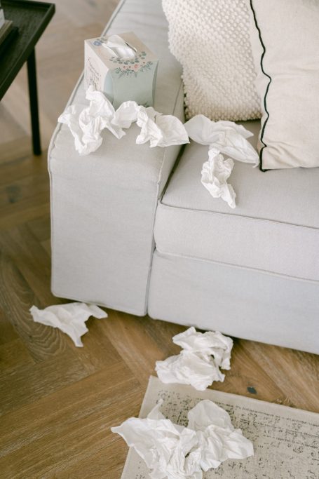 Ein Sofa mit verstreuten, zerknüllten Taschentüchern und einer Tissue-Box.